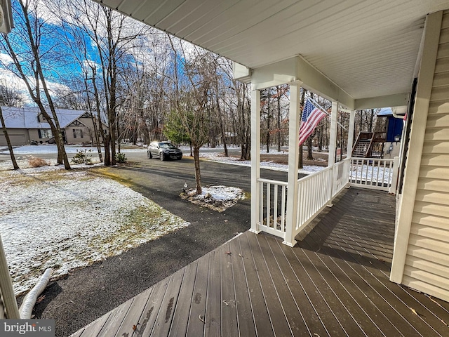 snow covered deck featuring covered porch