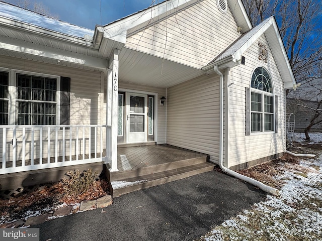 snow covered property entrance with a porch