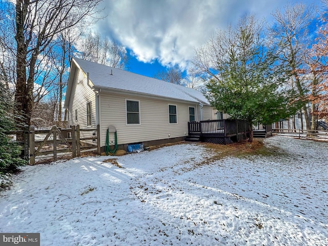 snow covered back of property featuring a wooden deck