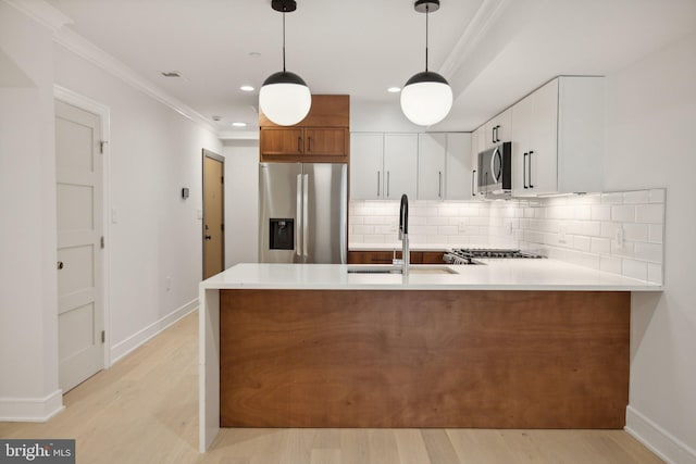 kitchen with stainless steel appliances, sink, white cabinets, light hardwood / wood-style floors, and hanging light fixtures