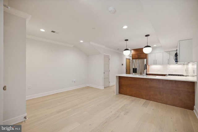 kitchen with stainless steel fridge, white cabinetry, hanging light fixtures, and light hardwood / wood-style flooring