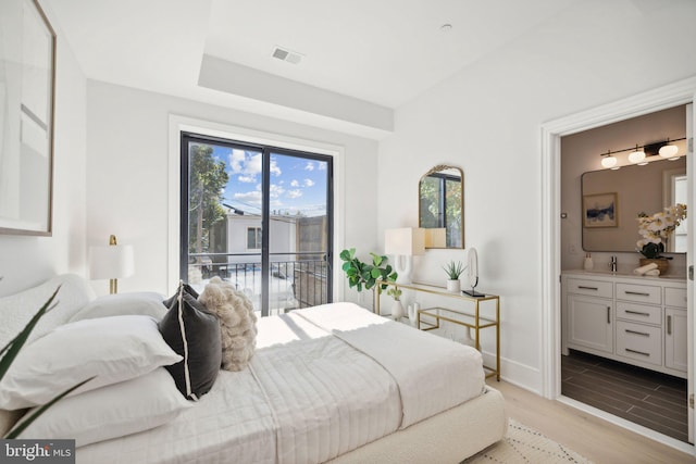 bedroom with access to exterior, ensuite bathroom, and light wood-type flooring