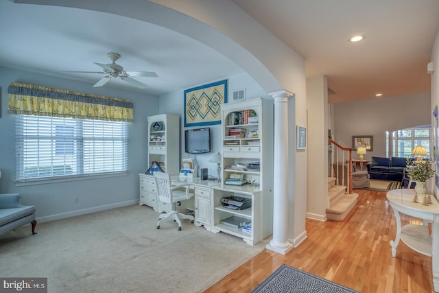 carpeted home office with decorative columns and ceiling fan