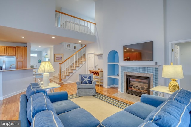 living room with a fireplace, a towering ceiling, and light hardwood / wood-style flooring