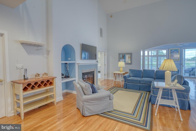 living room featuring built in shelves, hardwood / wood-style floors, and a high ceiling