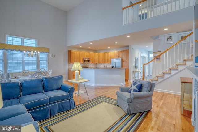 living room with light hardwood / wood-style flooring, a high ceiling, and a notable chandelier