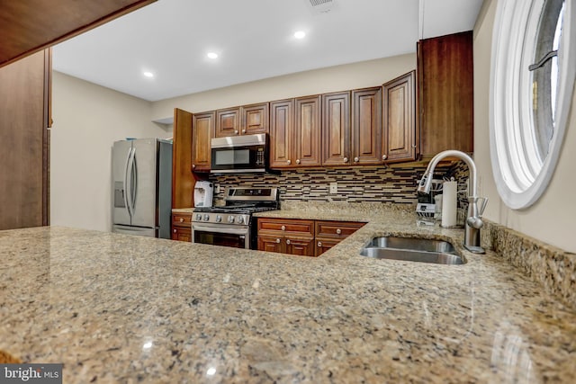 kitchen featuring backsplash, sink, light stone countertops, and stainless steel appliances