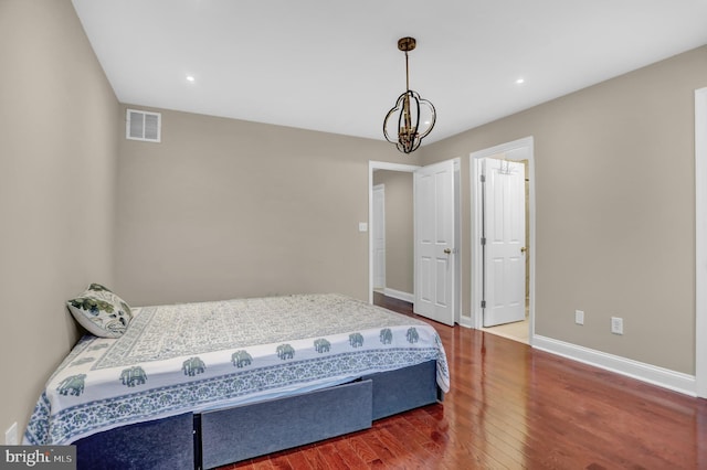 bedroom with hardwood / wood-style floors and a notable chandelier