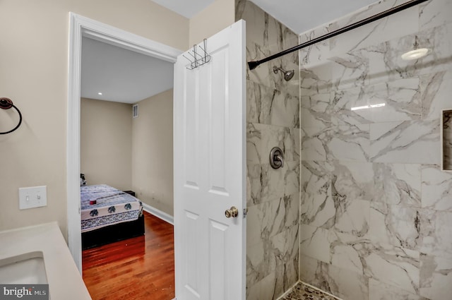 bathroom with tiled shower and hardwood / wood-style floors