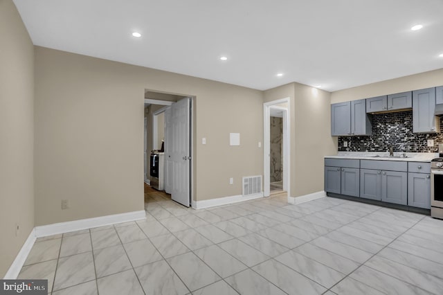 kitchen featuring decorative backsplash, electric stove, gray cabinetry, and sink