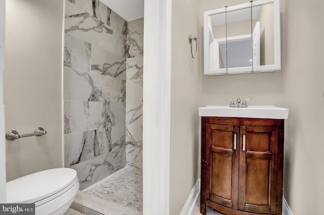 bathroom featuring toilet, vanity, and tiled shower