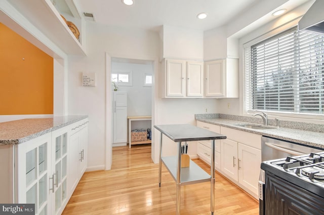 kitchen featuring a center island, white cabinets, sink, light hardwood / wood-style floors, and stainless steel range oven