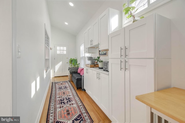 kitchen with light hardwood / wood-style flooring, white cabinets, and lofted ceiling