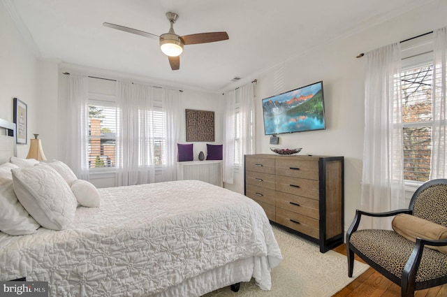 bedroom with ceiling fan, wood-type flooring, and crown molding