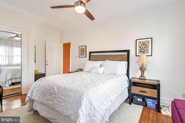 bedroom with hardwood / wood-style floors, ceiling fan, and ornamental molding