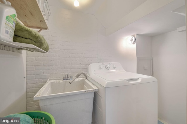 laundry room with sink, brick wall, and washer / dryer