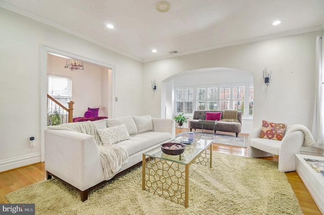 living room featuring light wood-type flooring, crown molding, and an inviting chandelier