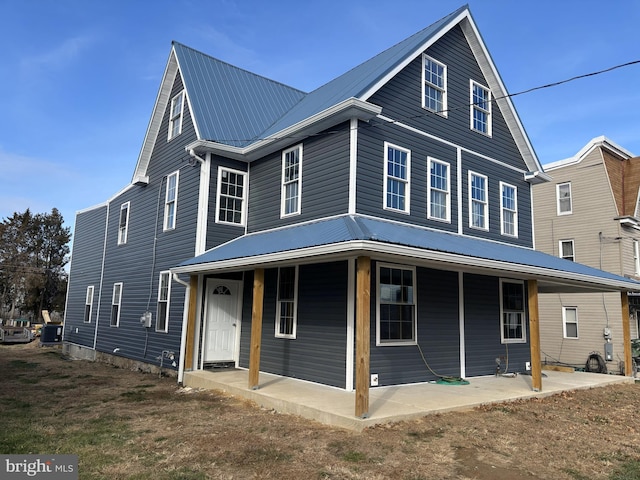 view of front of home with a porch, metal roof, and a patio