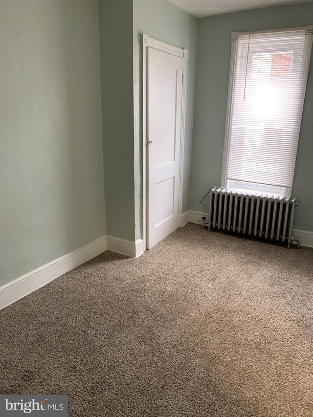 carpeted spare room featuring radiator