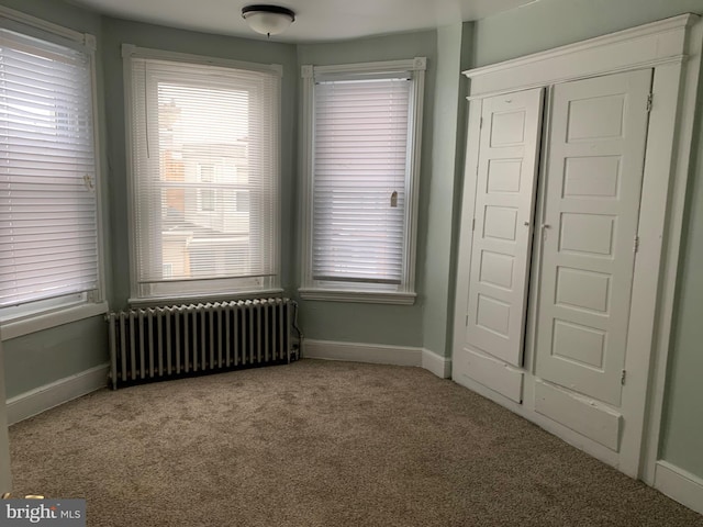 unfurnished bedroom with light colored carpet and radiator