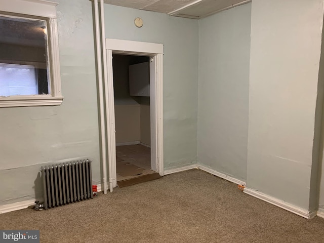 spare room with dark carpet and radiator heating unit