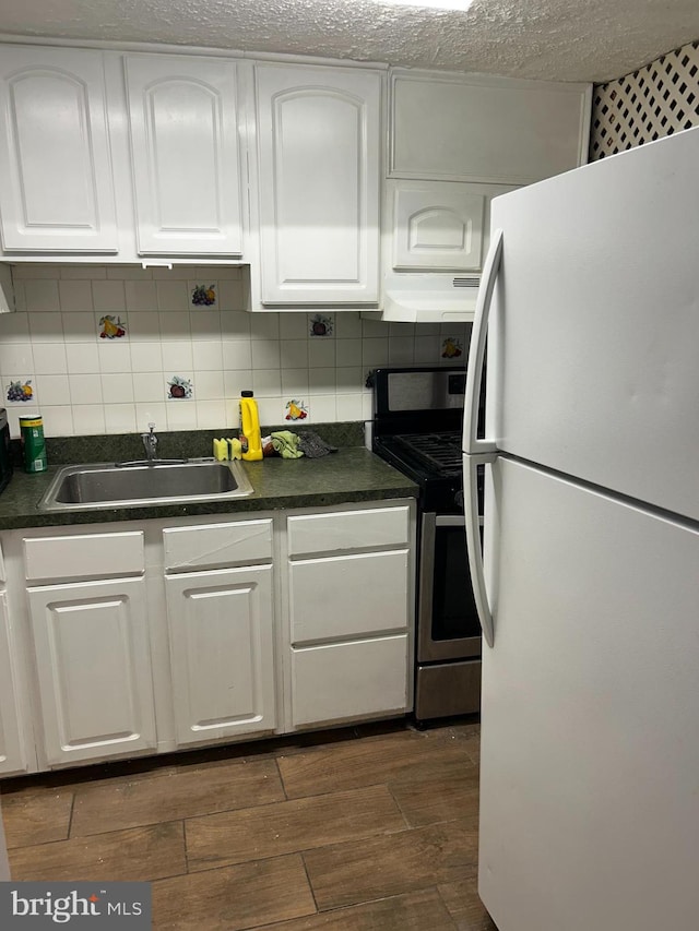 kitchen featuring stainless steel range, sink, white fridge, extractor fan, and white cabinets