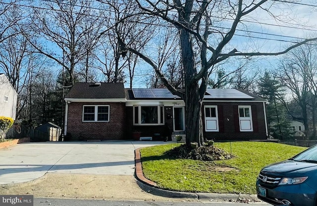 single story home featuring a front lawn, a shed, and solar panels