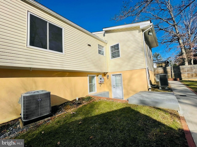 back of property with a lawn, cooling unit, and a patio