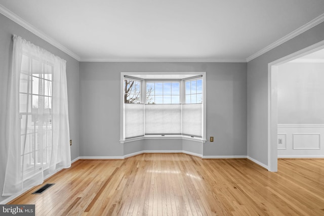 empty room with light wood-type flooring and crown molding