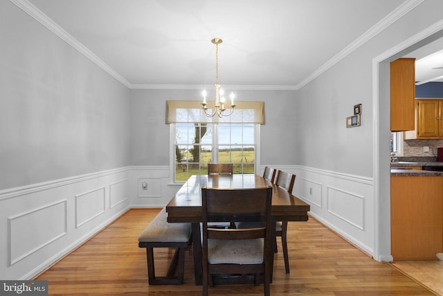 dining room with a chandelier, light hardwood / wood-style floors, and ornamental molding