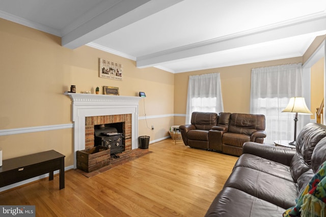 living room featuring beamed ceiling, ornamental molding, a wood stove, and light hardwood / wood-style flooring