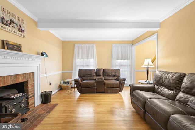 living room featuring a brick fireplace, ornamental molding, and light hardwood / wood-style flooring