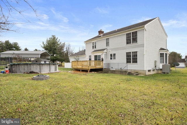 back of house with a swimming pool side deck, a yard, cooling unit, and an outdoor fire pit