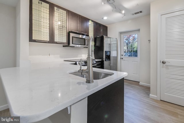 kitchen with visible vents, light wood-style flooring, a peninsula, stainless steel appliances, and a sink