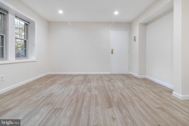 spare room featuring light wood finished floors, baseboards, and recessed lighting