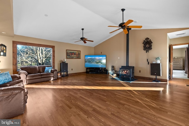 living room featuring a wood stove, hardwood / wood-style flooring, vaulted ceiling, and ceiling fan