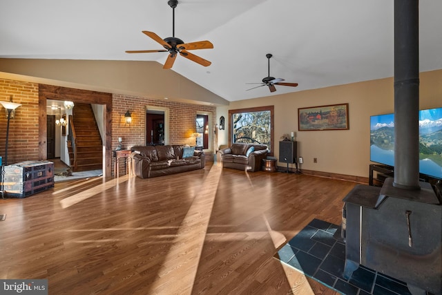 living room featuring dark hardwood / wood-style flooring, brick wall, ceiling fan, a wood stove, and lofted ceiling