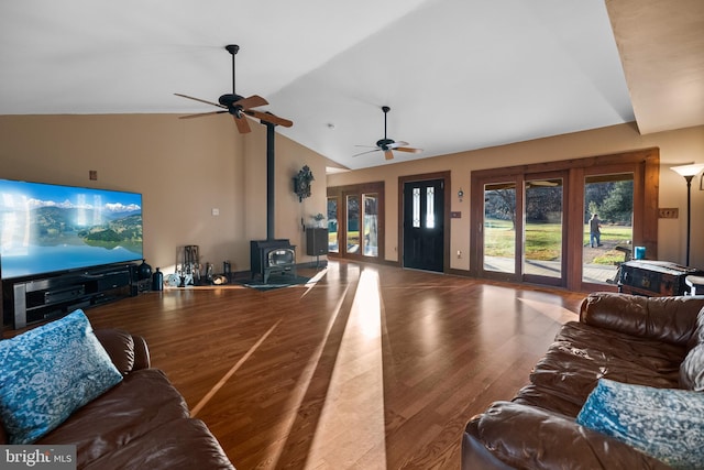 living room with hardwood / wood-style flooring, a wood stove, ceiling fan, and lofted ceiling