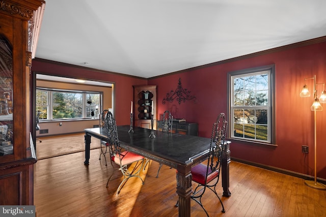 dining space featuring a healthy amount of sunlight, light hardwood / wood-style floors, and crown molding