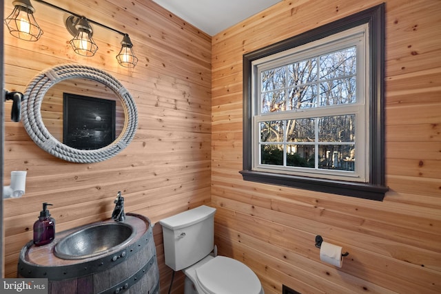 bathroom with vanity, toilet, and wooden walls