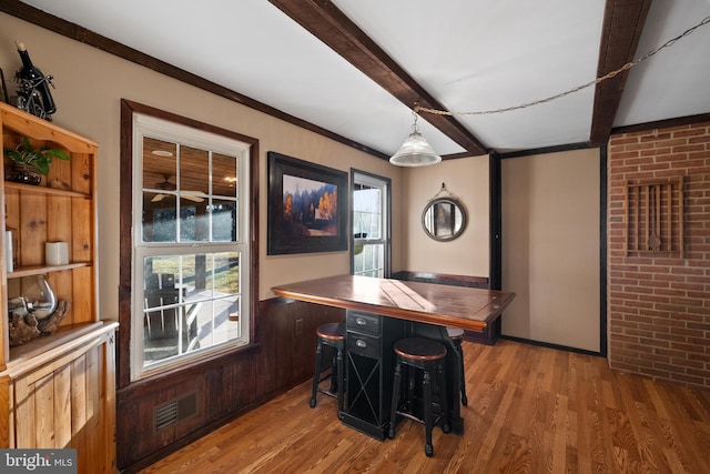 bar featuring wood-type flooring, hanging light fixtures, and a wealth of natural light