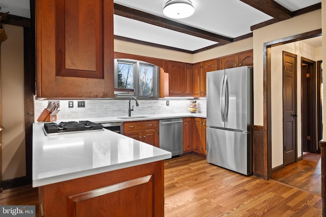 kitchen with beam ceiling, sink, decorative backsplash, appliances with stainless steel finishes, and light wood-type flooring