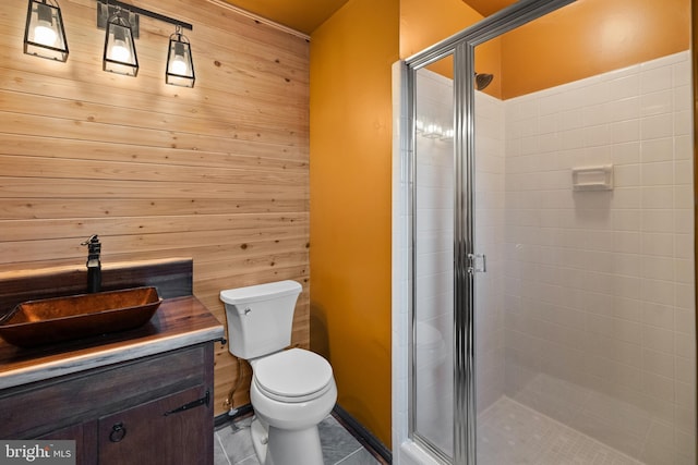 bathroom featuring vanity, tile patterned flooring, toilet, a shower with shower door, and wood walls