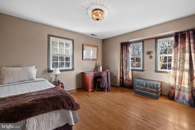 bedroom with light hardwood / wood-style floors and multiple windows