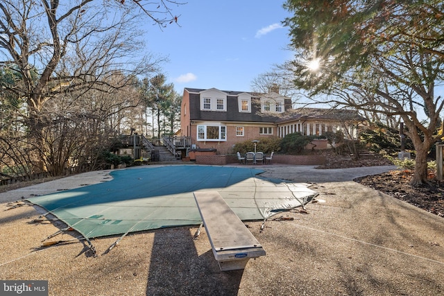 view of swimming pool featuring a diving board, a patio, and a deck