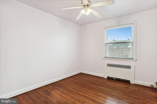 empty room featuring radiator, ceiling fan, and dark hardwood / wood-style flooring