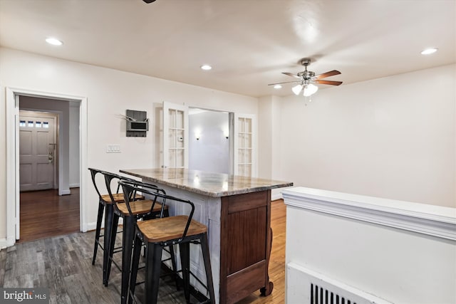 kitchen featuring french doors, dark hardwood / wood-style floors, ceiling fan, a kitchen island, and a breakfast bar area