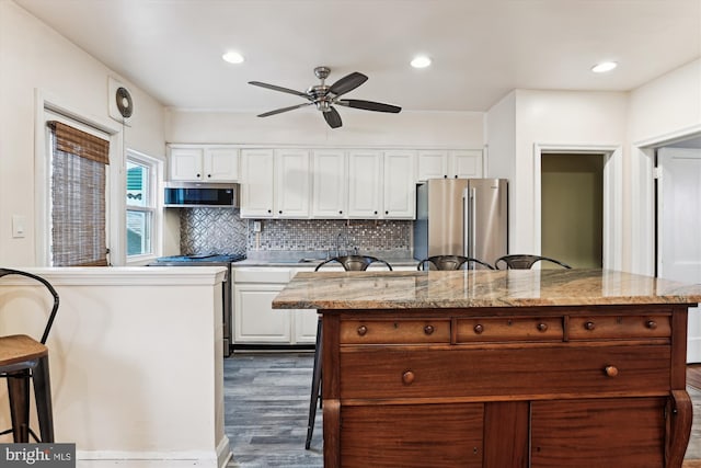 kitchen with dark hardwood / wood-style floors, ceiling fan, a kitchen island, white cabinetry, and stainless steel appliances