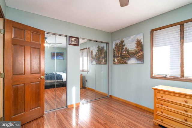 bedroom featuring multiple closets, ceiling fan, and light hardwood / wood-style flooring