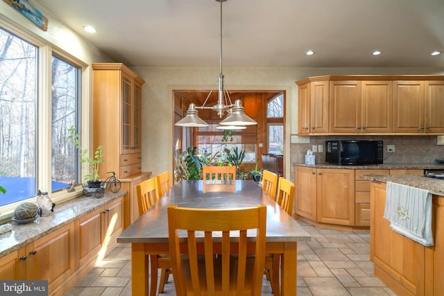 kitchen featuring decorative backsplash, decorative light fixtures, a kitchen island, and light stone counters